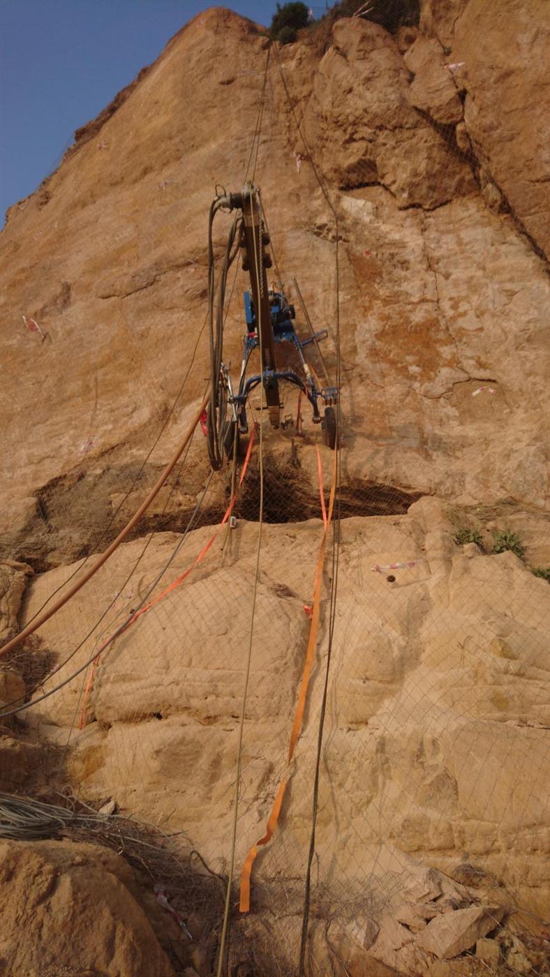 Drill rig boring vertical holes in a rock face