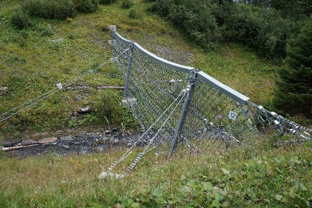 Flexible ring-net barrier spanning a torrent channel