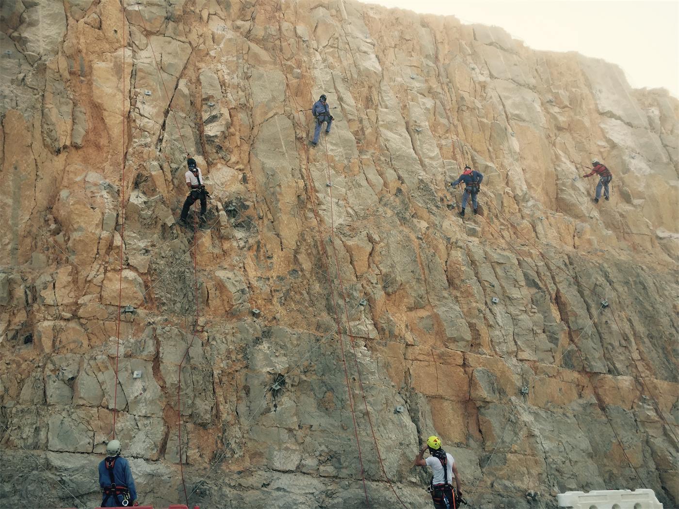 Multiple rope access technicians on a high rock face