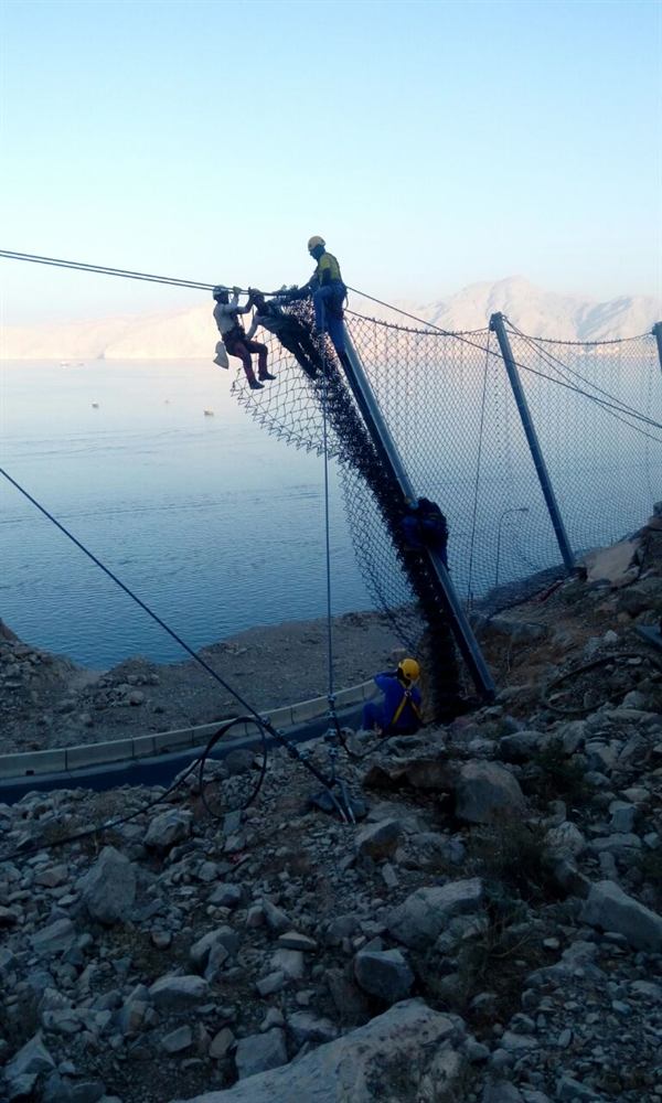 Rope-access barrier installation above a marina
